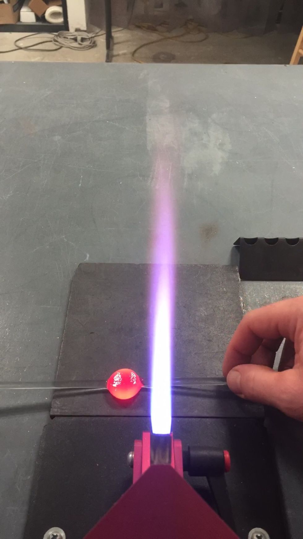 Flip it over and press the other side onto the marver, creating a flat patty of glass. You may want to go back and forth, pressing each side onto the marver until it's flat and not very hot.