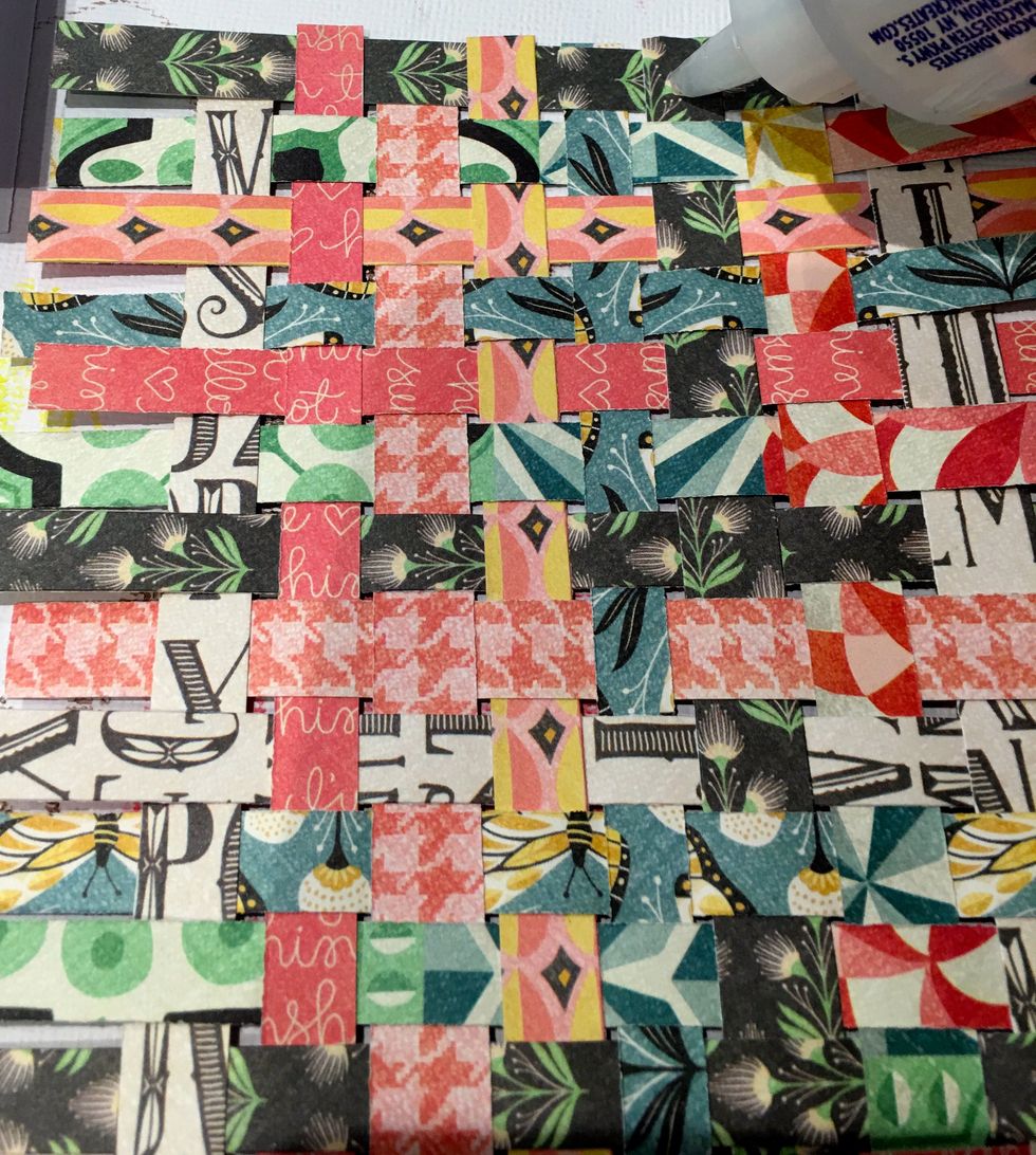 Flip over the weaved paper and apply glue back and forth across the rows of paper.