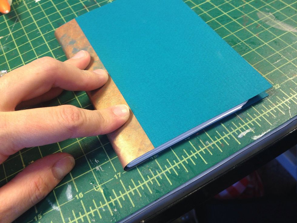 Flip the book over, wrap the paper around the spine, and press it down on the back.