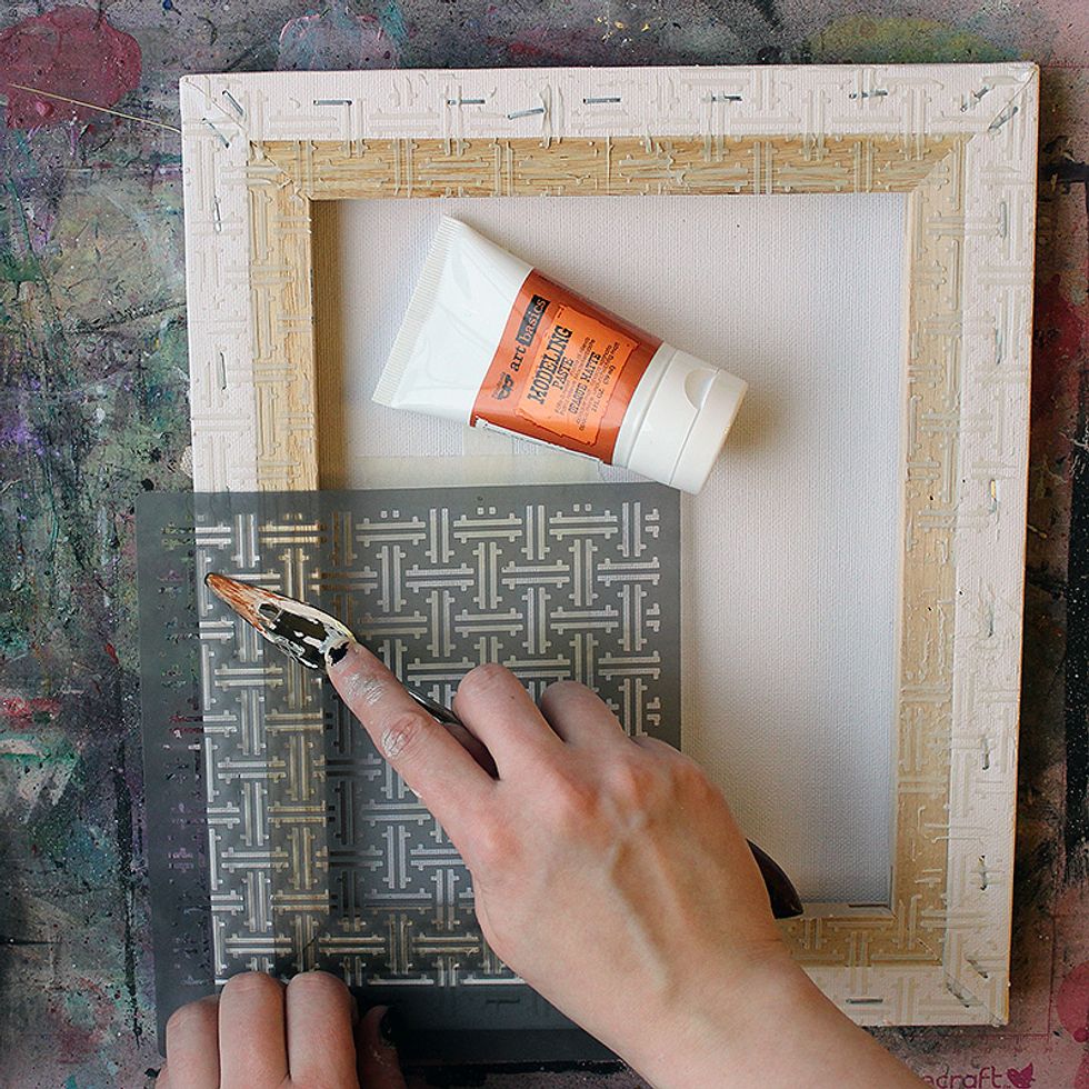 Flip the canvas over and start by adding Modeling Paste through a stencil to the frame of the canvas.