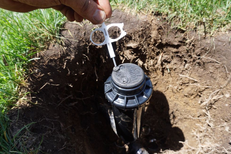 Flip the key over for the arc/throw adjustment side. You stick it in the arrow and turning clockwise shortens/widens the spray, while counterclockwise increases the distance and narrows the spray.