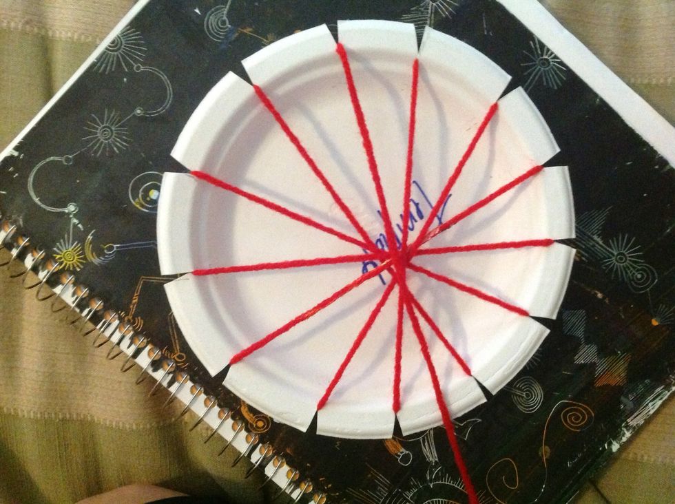 Flip your paper plate loom over. Bring your yarn across the center.
