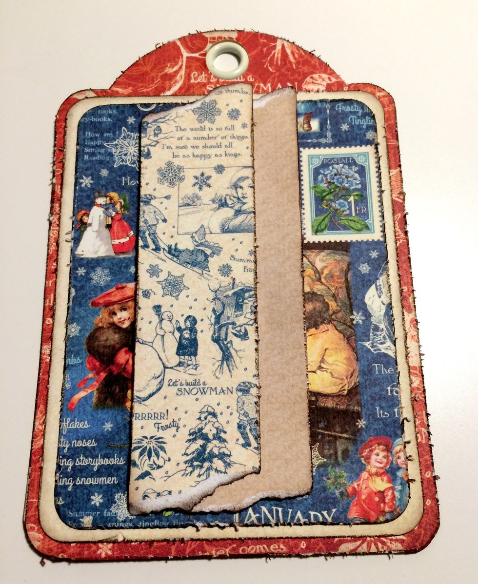 Foam square the cream strip of paper 1" from the right and 1/2" from the bottom of the tag. Foam square the blue/cream patterned paper 1" from the left and 1/2" from the bottom of the tag.