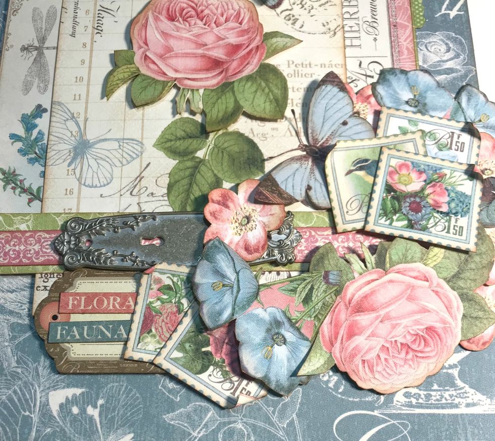 Foam square the sticker tag 1.5" from the left of paper. Adhere words to tag. Adhere 2 stamps to the left of the tag. Roll down 1 corner on each stamp. Lift up single pink flower & adhere door knob.