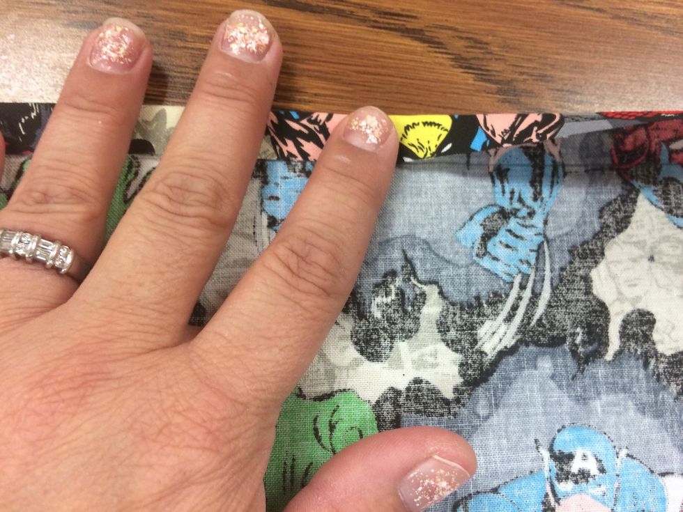 Fold 1/2" of the top edge of the pocket to the back side. Fold it down to the pencil line