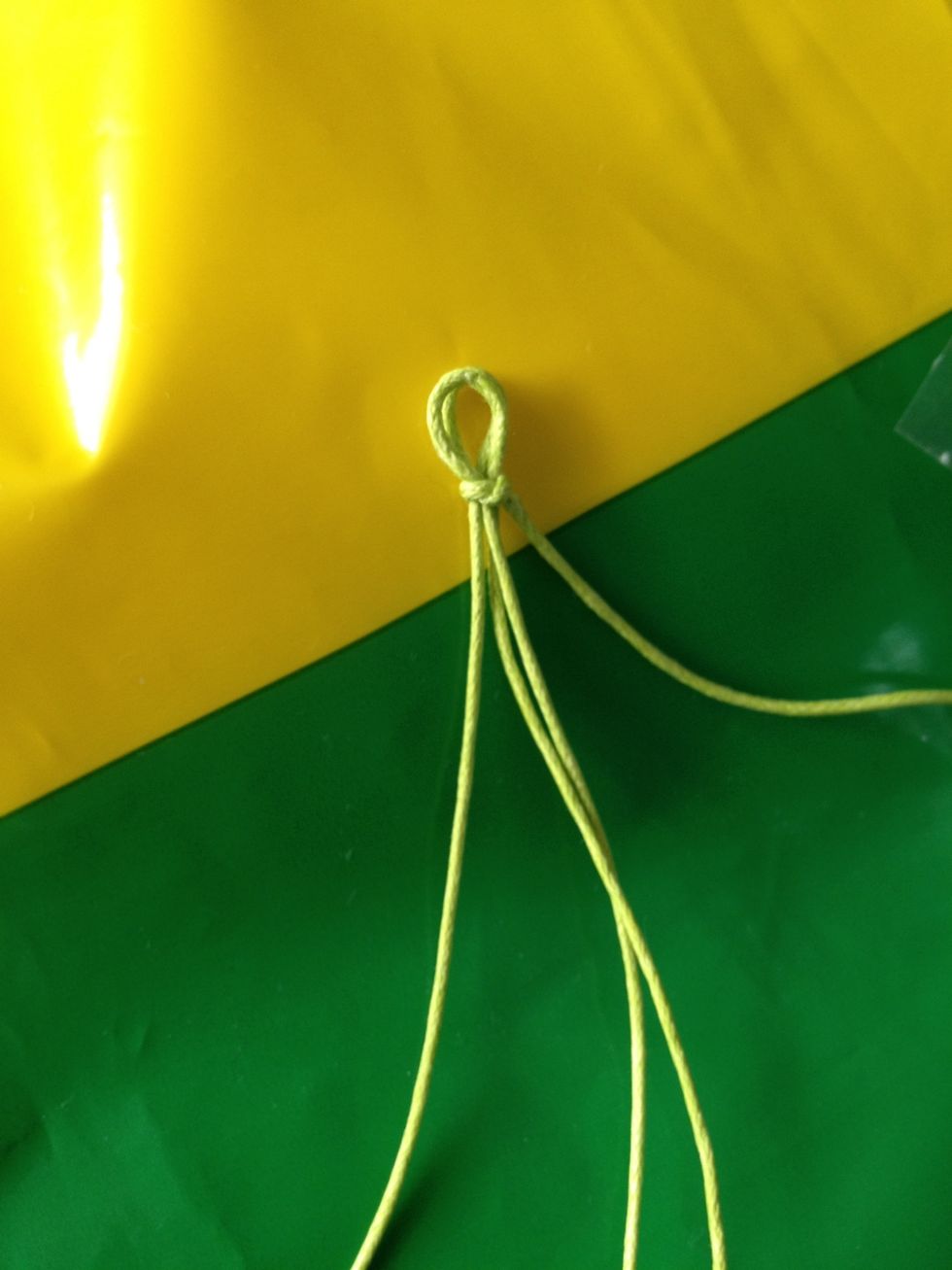 Fold 57cm thread in half. Align the 38cm thread with the 2 longer ends. Tie remaining string into knot at the top. You should have 3 long strings and a shorter one.