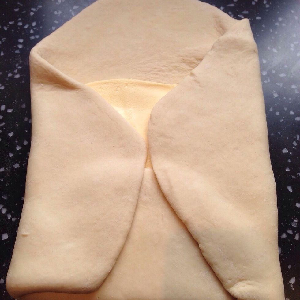 Fold a flap of dough over the butter so the point of the dough reaches the centre of the butter slab. Flatten the dough with your palm gently to seal the seams