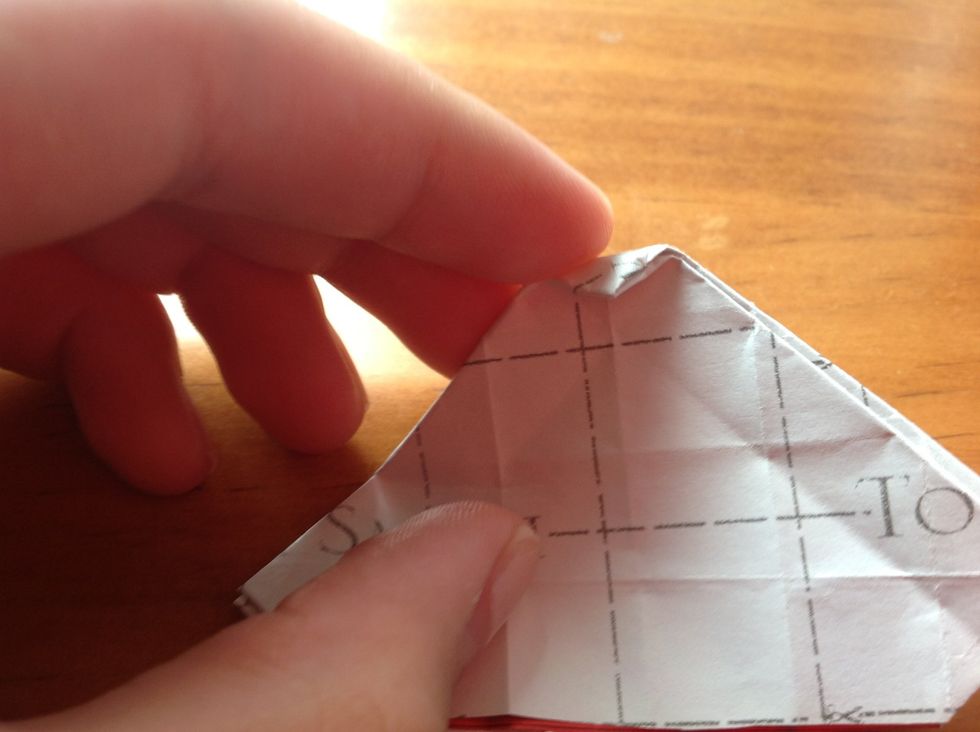 Fold a triangle from the top up to the first visible line. (This is why proper folding from before is imperative). Fold it back to the other side too for good measure.