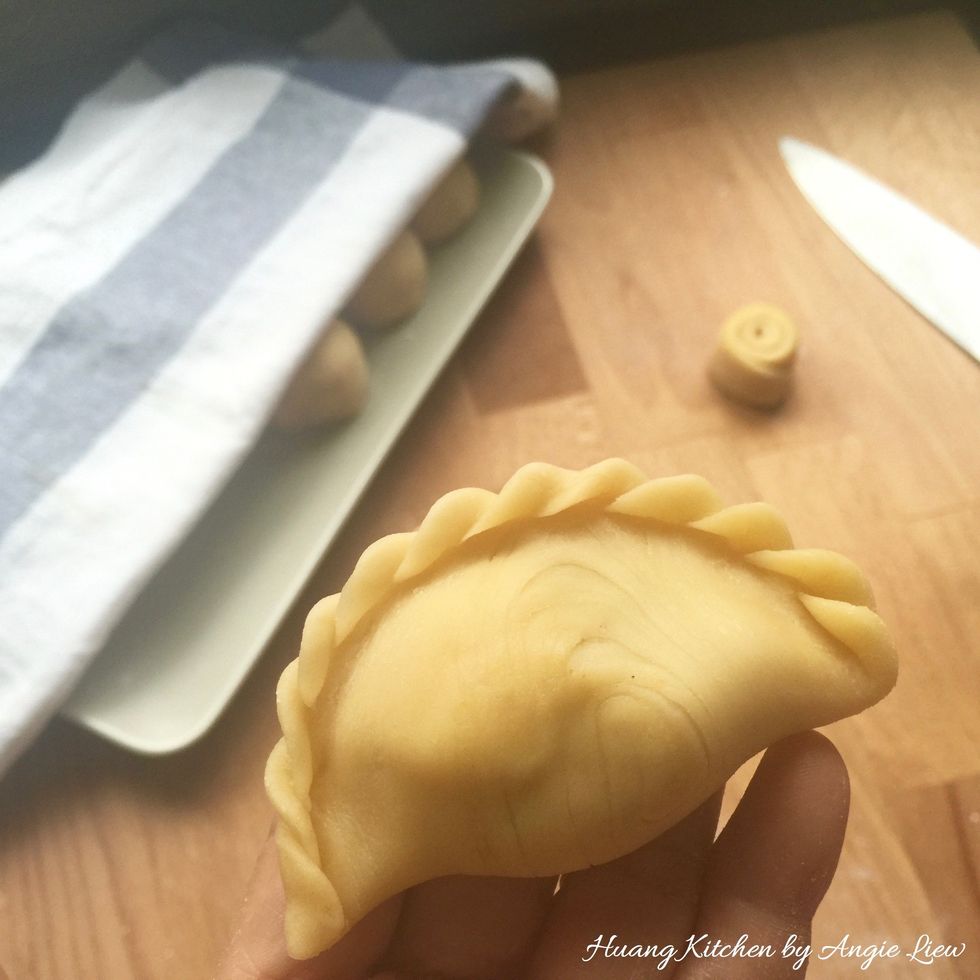 Fold and shape into a half-moon and pinch the edges together to seal in the filling. Pleat up the edges neatly and decoratively.