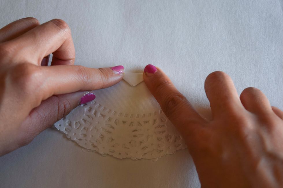 Fold down the top tip of the doily and glue that down. The resulting horizontal line will form the waist of the dress. This is the back of your skirt.