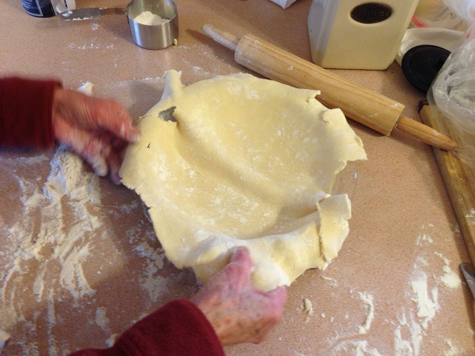 Fold out so it covers the whole pan. Make sure to lightly press it into place so there's not air bubbles on bottom. Any torn sections can be repaired with some water and pressing the dough together.