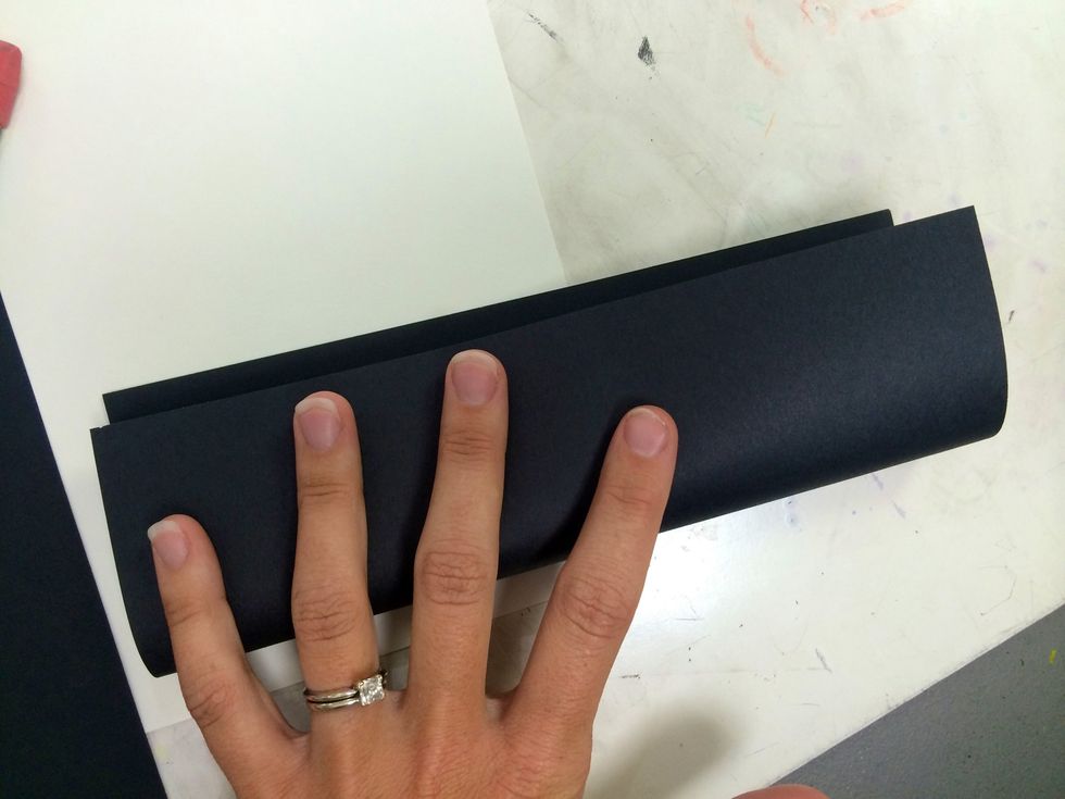 Fold the black paper in half along the long line of symmetry.