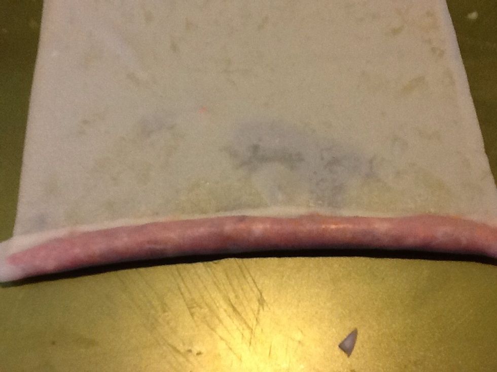 Fold the bottom of the wrapper over the mixture and press down to compress into a smooth roll.