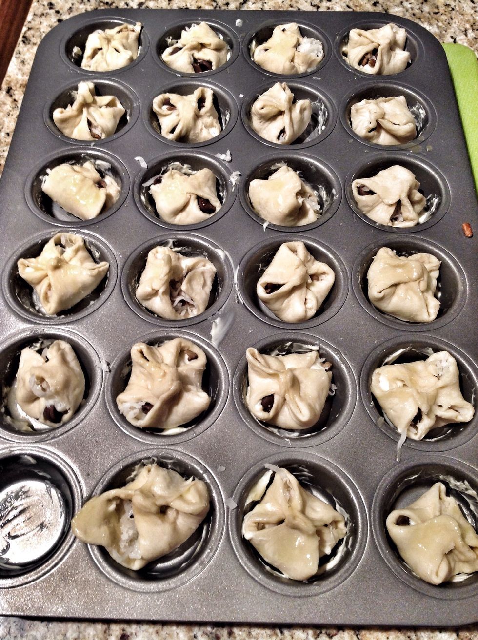 Fold the corners of your pastry cuts, over the mixture to prepare for baking. Brush the pastries with remaining melted butter.