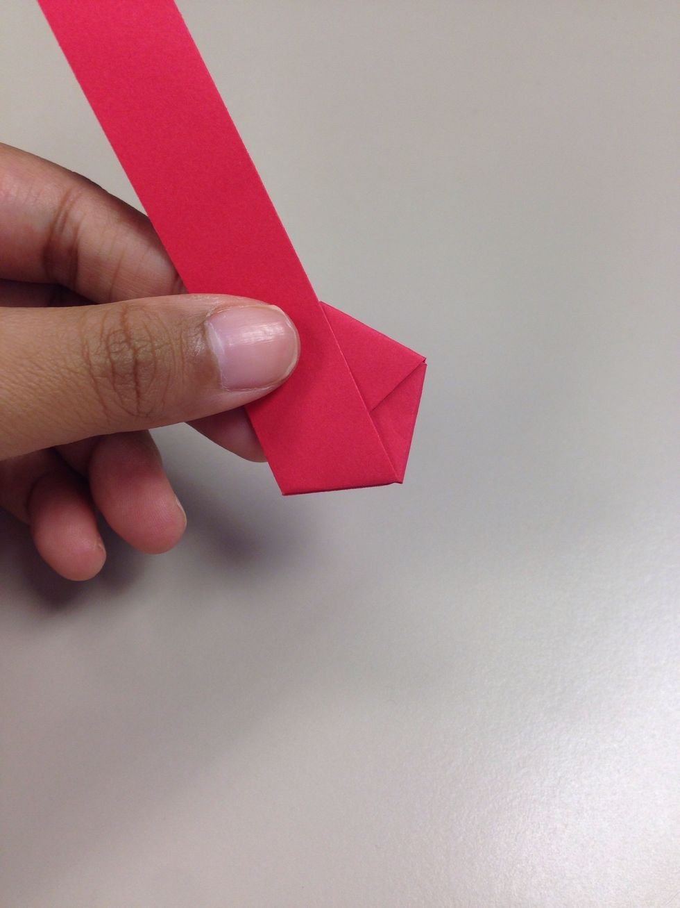 Fold the longer end over the pentagon as much as possible