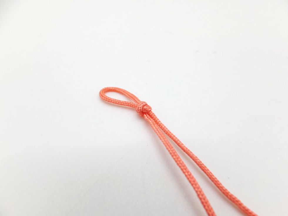 Fold the orange cord in half and tie a double connection knot so that you have a loop.