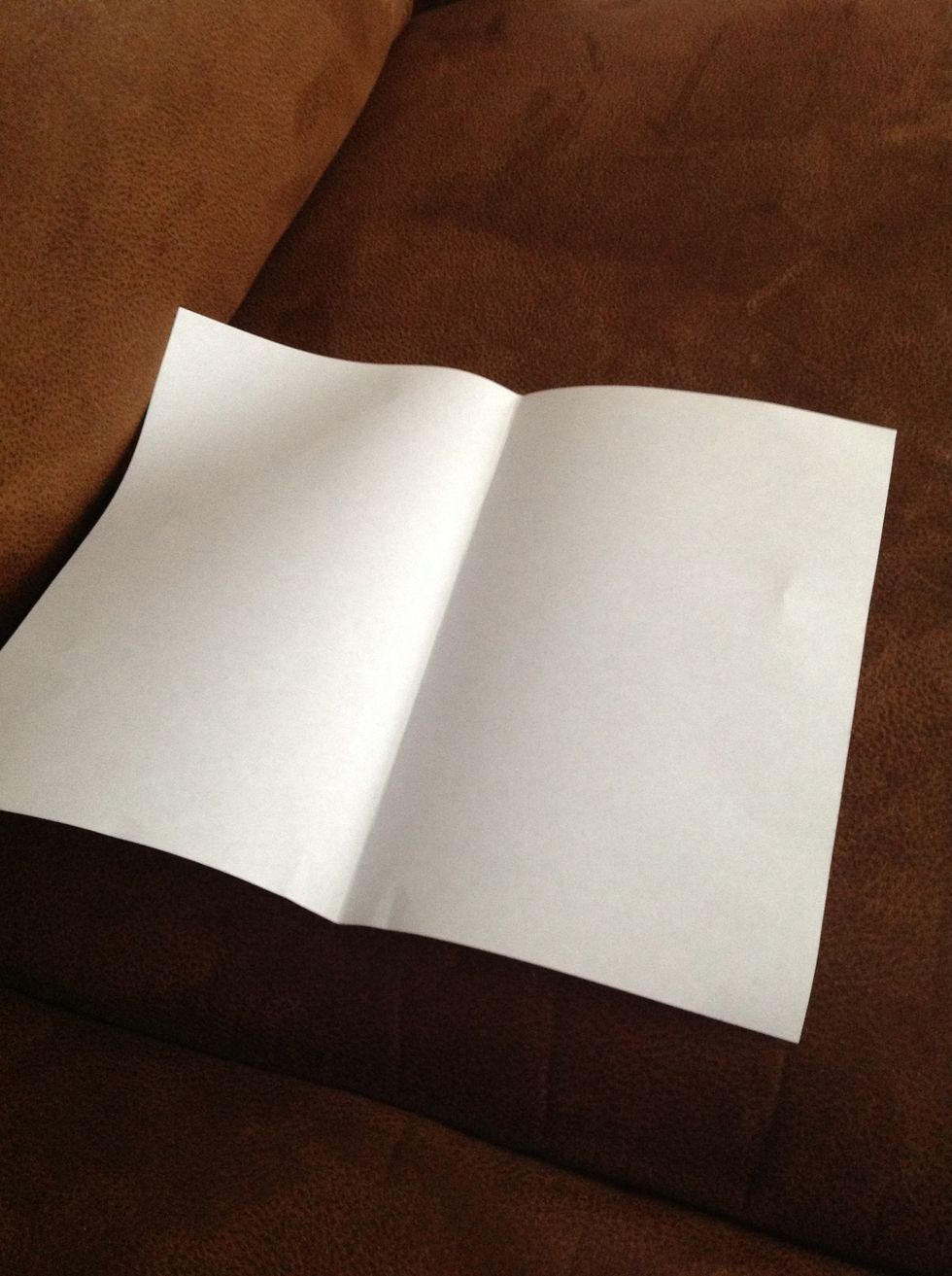 Fold the paper along the width then unfold it to create a crease along its center.