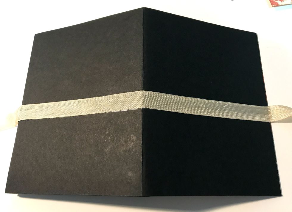 Fold the right panel in. Flip the card base over. Adhere the gold ribbon to the middle of the card base. Leave the tails of the ribbon as long as you'd like for creating a bow.