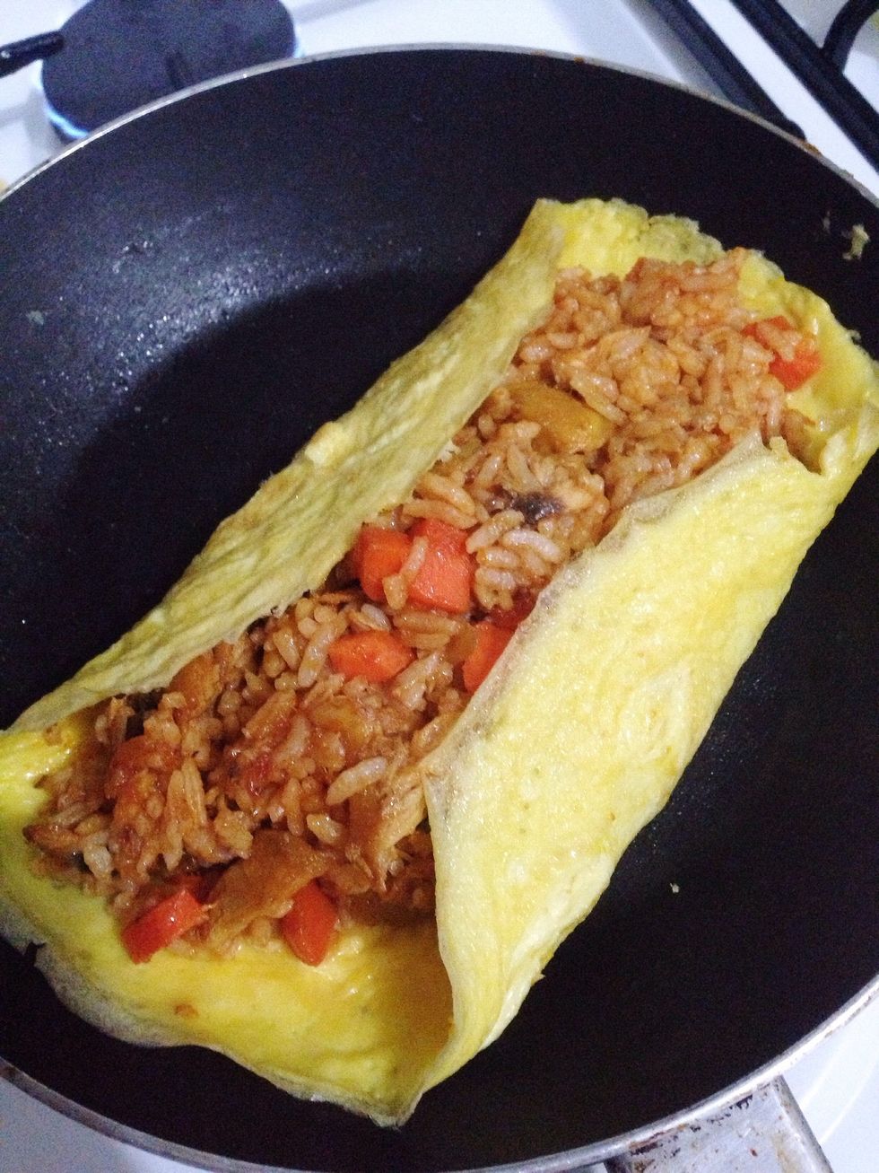 Fold the sides of omelet over the rice. Do this when your egg is 80% cooked..if your egg fully cooked, it will crack/tear when you fold. Then let it cook thorougly & remove from heat