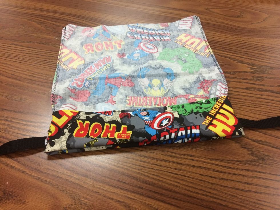 Fold the top edge 1 1/2" down (my example is folded too far down) this will be the casing for the straps along the top. You will guide the straps through the opposite hole along the top of the bag!