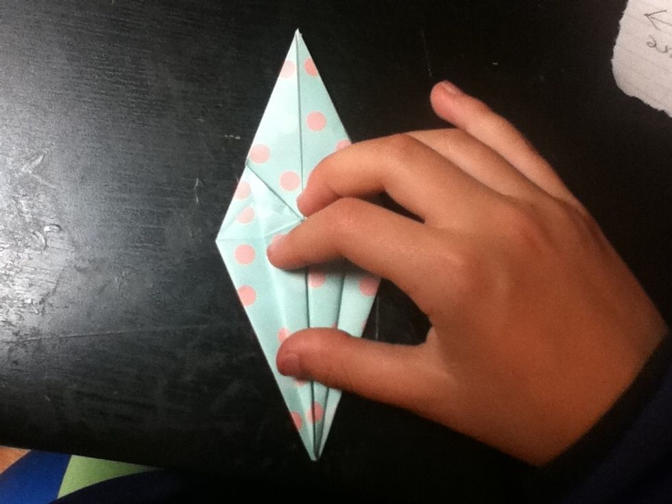 Fold the top layer of the sides inward. This is similar to step 12. Make sure that you can still open the bottom. Also make sure that your pointy end has a split down the middle, as illustrated next.