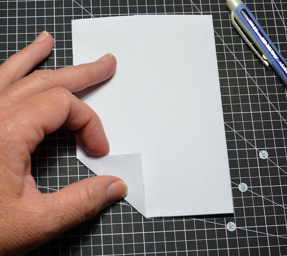 Fold up the bottom left edge to line with the glued paper edge as shown.