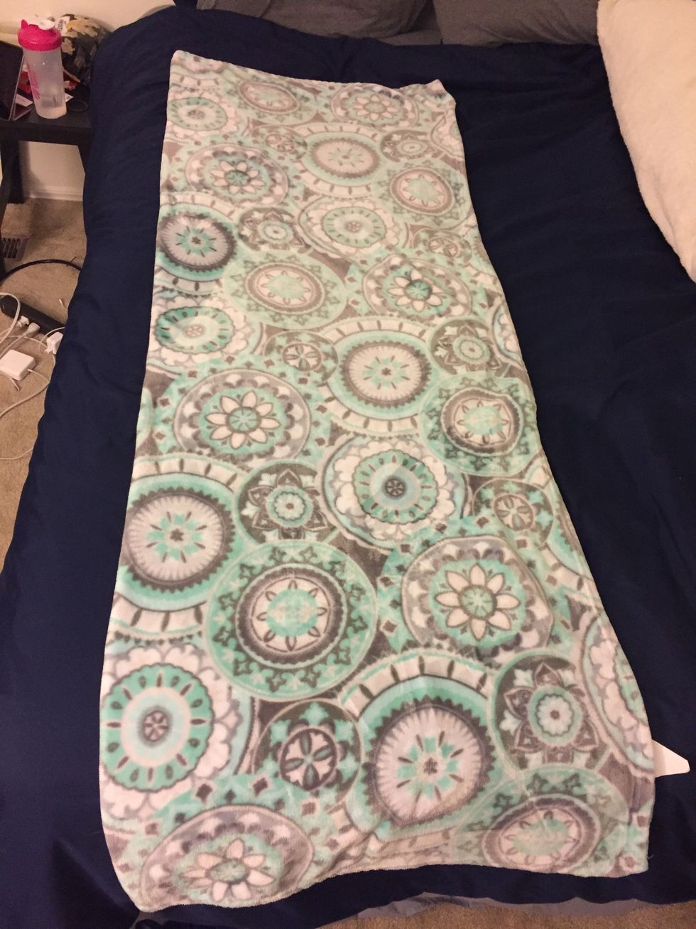 Fold your blanket in half (hot dog style). Do this by bringing the edge of the longer side to meet the opposite edge of the other side of the blanket.