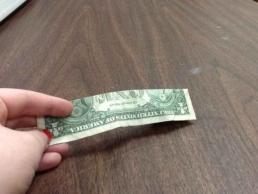 Fold your dollar in half hot-dog style, and make sure the ends meet at exactly the right spot, as it's important for the next steps. Crease the fold sharply with your fingernails.