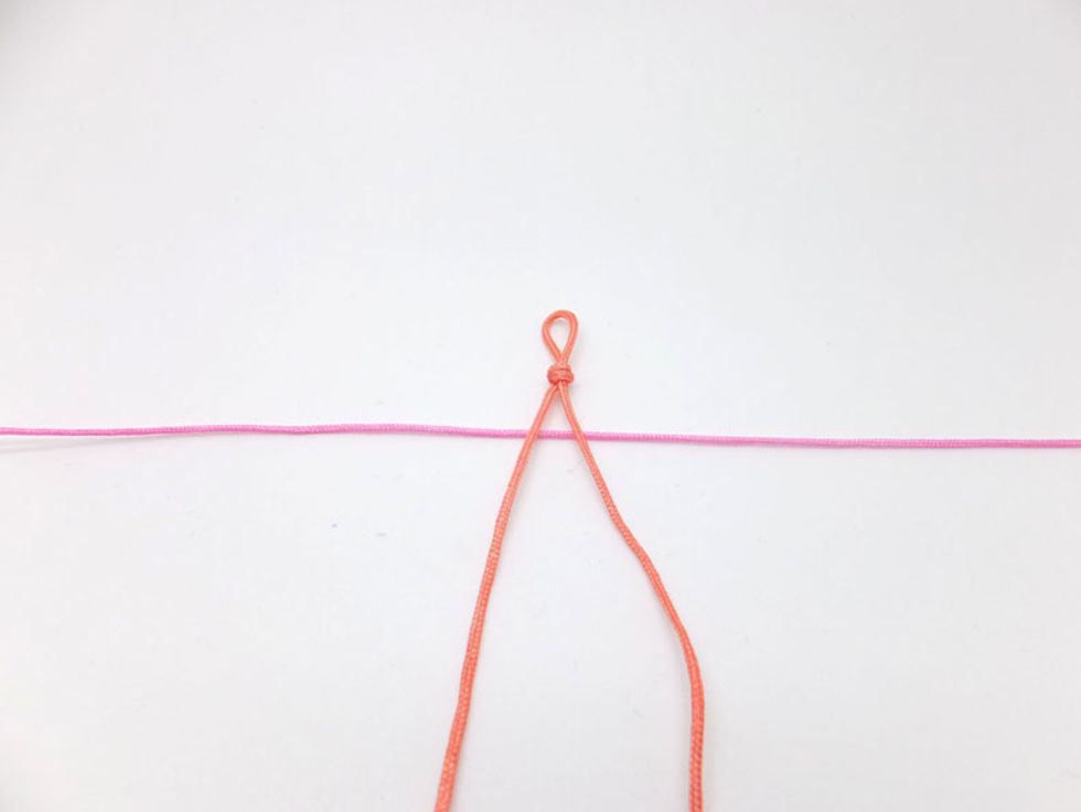 Fold your knotting cord (pink cord) in half to find the center and place it under the knot.