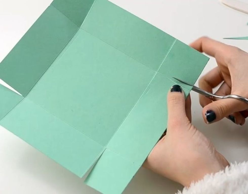 Following the scored line, cut a V shape at each corner, like in the photo.