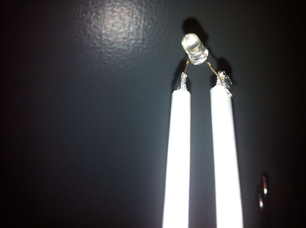 For demonstration purposes we're going to use this drill/generator to light this LED. So connect the negative and positive of the LED to the foil protruding from the ends of the straws.