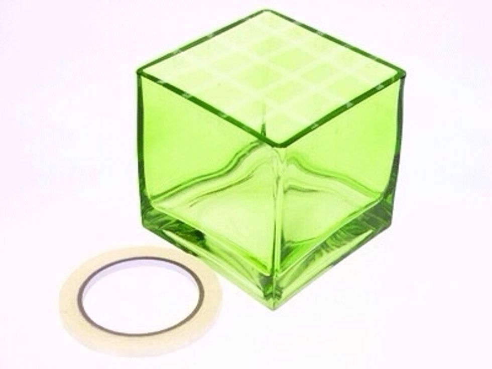 For easy design mechanics use clear waterproof tape, this grid will provide support for the flower stems and is essential when designing in cube vases.