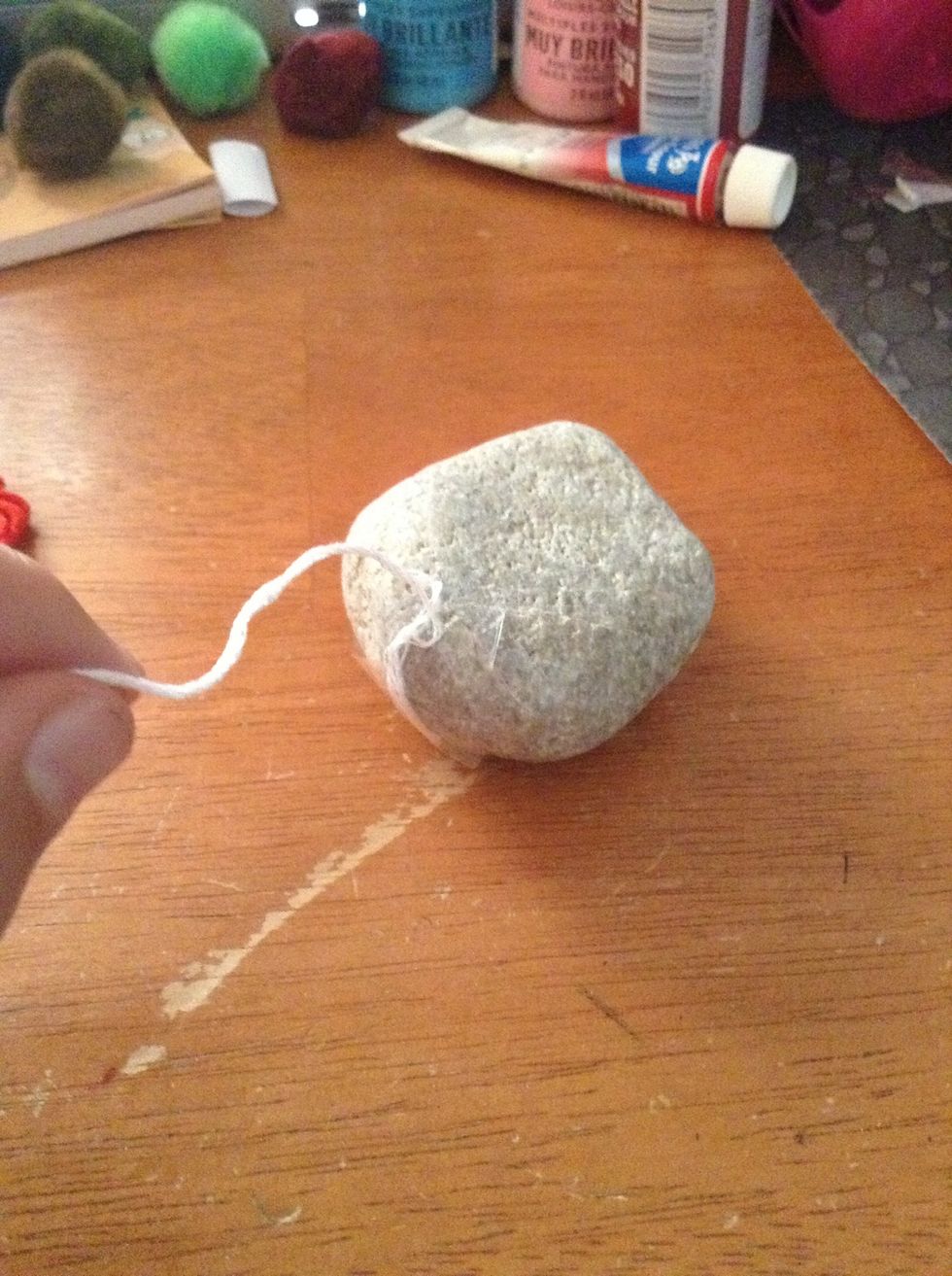 For paints, paint the whole rock and skip to step 9. For string, start by taping or gluing one end of the string to the rock