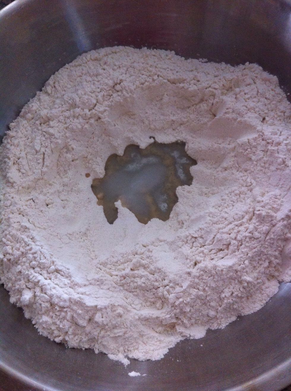 For the dough: Put flour on big container. Pour oil in the middle.