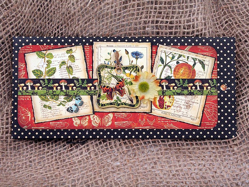 For the front of the envelope, add a belly band.  Cut a decorative strip & adhere only at the ends.  Top with a chipboard piece glued only to the decorative strip.  Then slip in some small cutaparts.