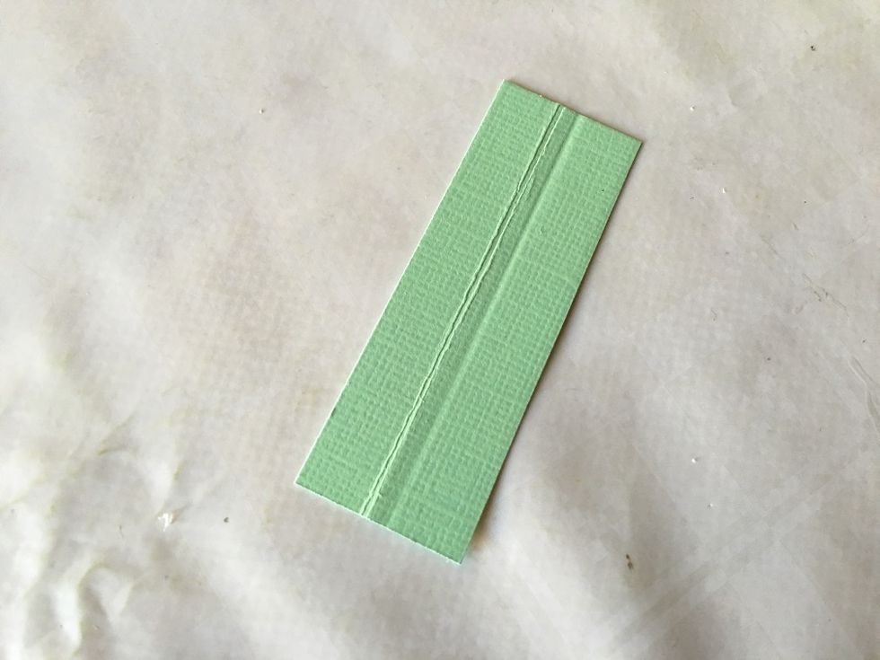 For the spine, cut a piece of cardstock of 7 x 2,3 cm (2\u00be x 7/8\u201d). Score at 1 cm (3/8\u201d) and 1,3 cm (\u00bd\u201d) on the 2,3 cm (7/8\u201d) side.