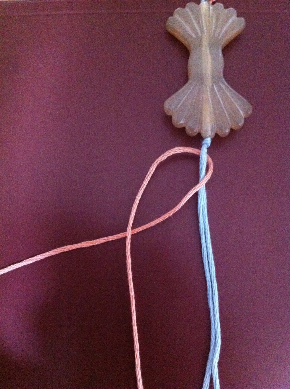 Form a 'P' with the pink cord. Look at the picture and take note that the cord I crossed from the right to the left, is over the blue, but under the other pink cord.
