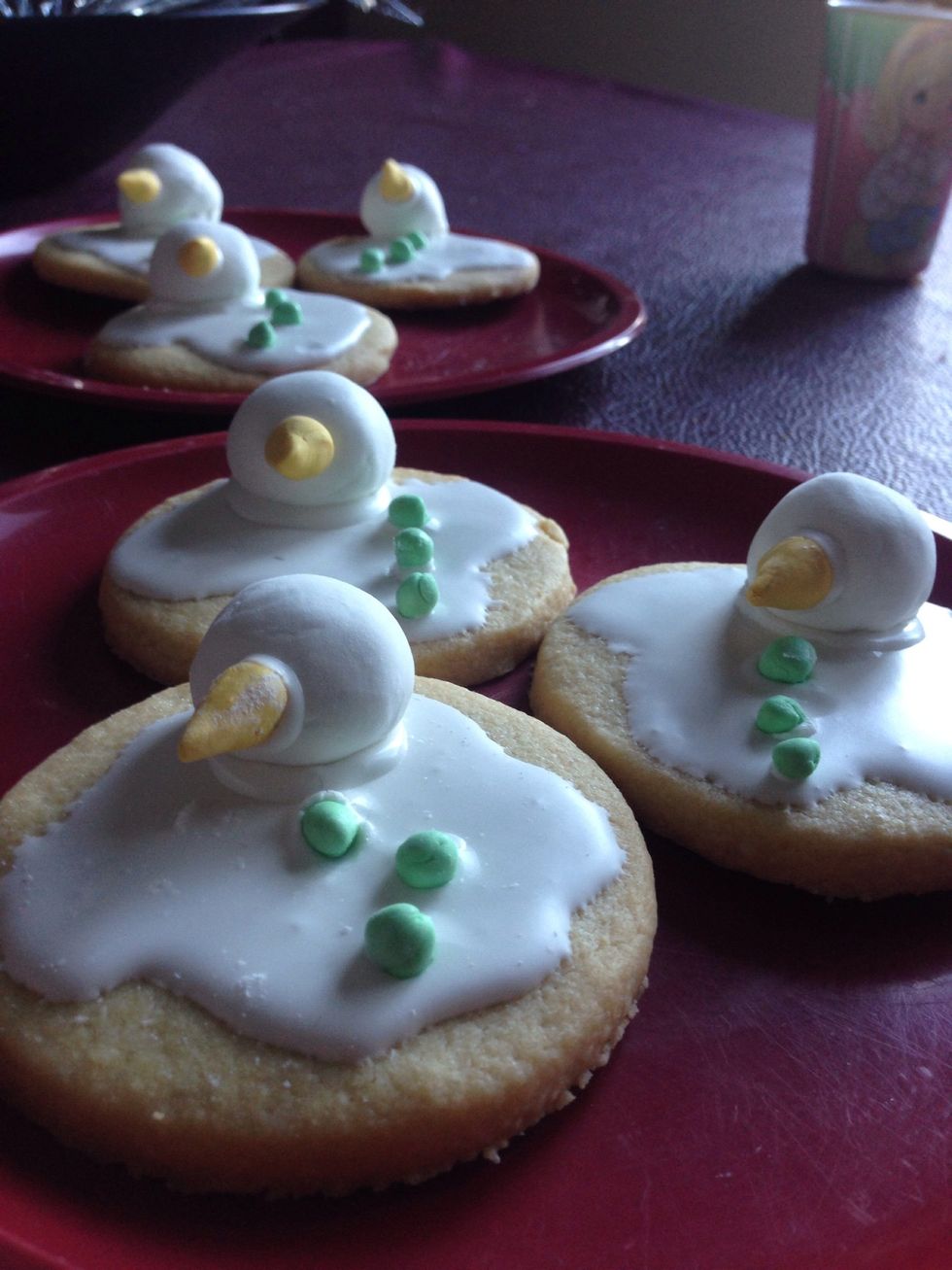 Form the head and add green and red (or yellow) food coloring to the rest of the fondant to form the nose and buttons. Stick them on the cookies with some icing