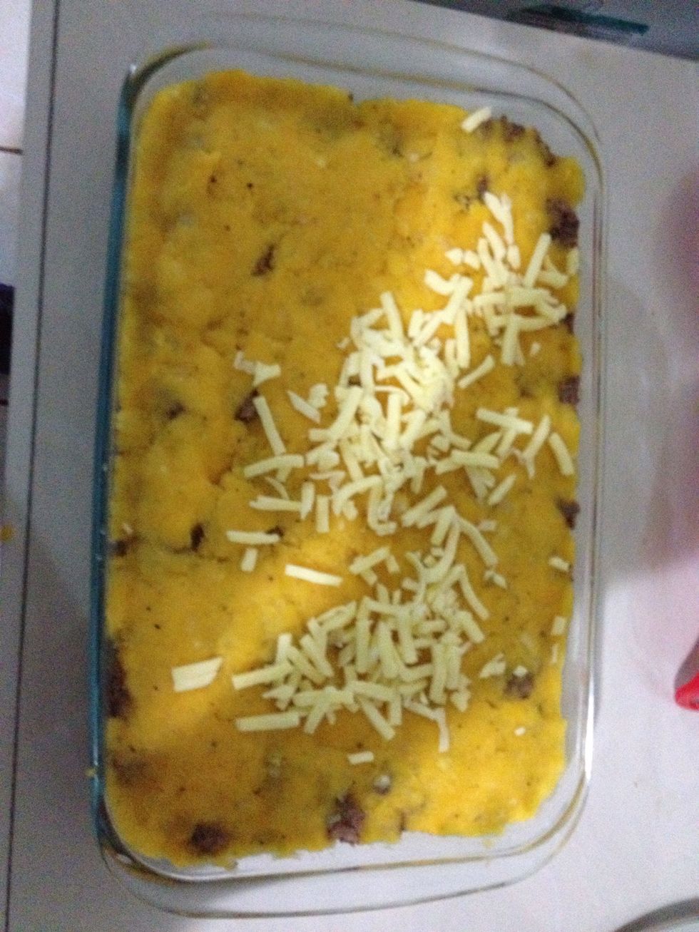 Formar la \u00faltima capa del pur\u00e9 de yuca y luego comenzar a esparcir una capa de queso tipo Mozzarella rallado.