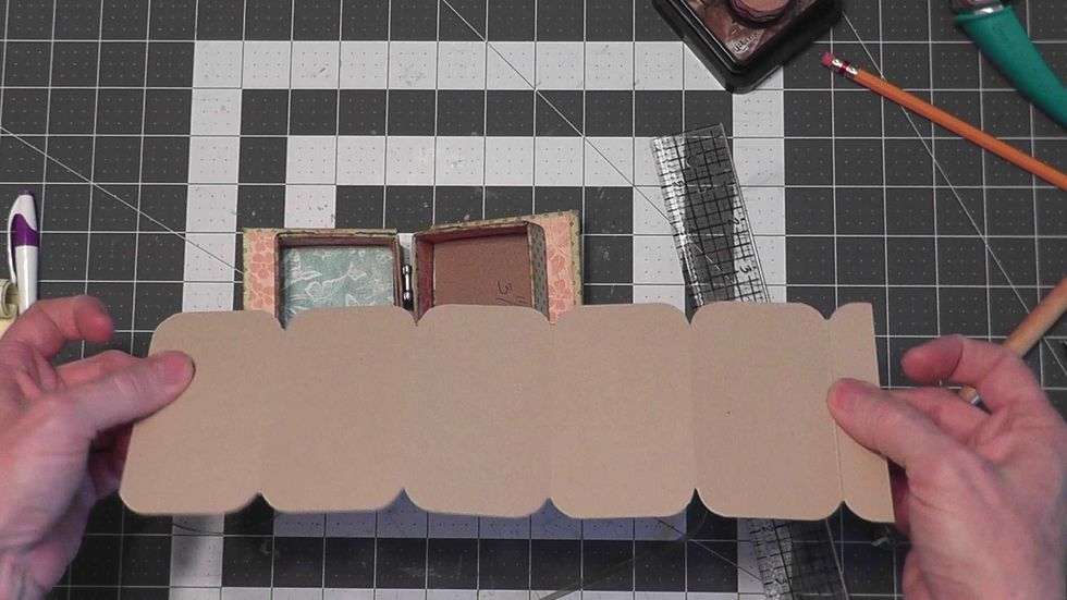 From Kraft cardstock, cut one piece 12" x 3 3/4". Score the 12" side at 2 1/4", 4 1/2", 6 3/4", 9" and 11 1/4" to fold up into the right side of the box.   See next step before attaching into the box.