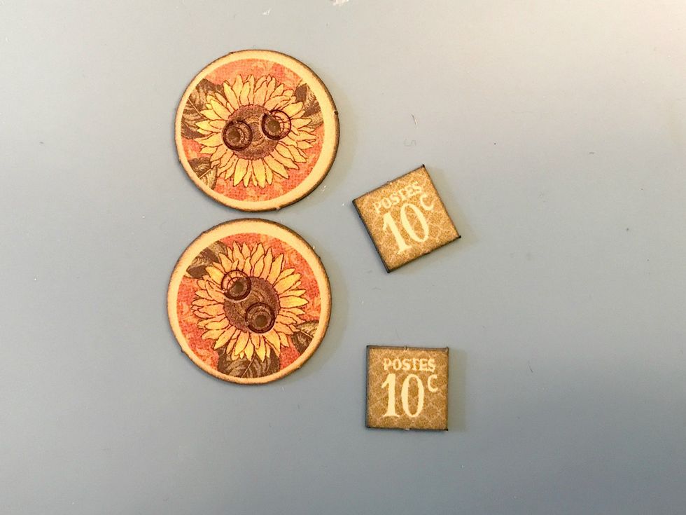 From the chipboard pieces, punch out two sunflower buttons and two post 10 cent squares. Ink the edges of the chipboard pieces with Black Soot Ink and a Blending Tool with foam.