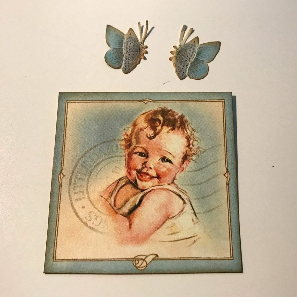 From the image paper, cut a baby square that measures 2 1/2" x 2 1/2". Fussy cut out two butterflies. Ink the edges of the images using Vintage Photo Distress Ink and a blending tool with foam.