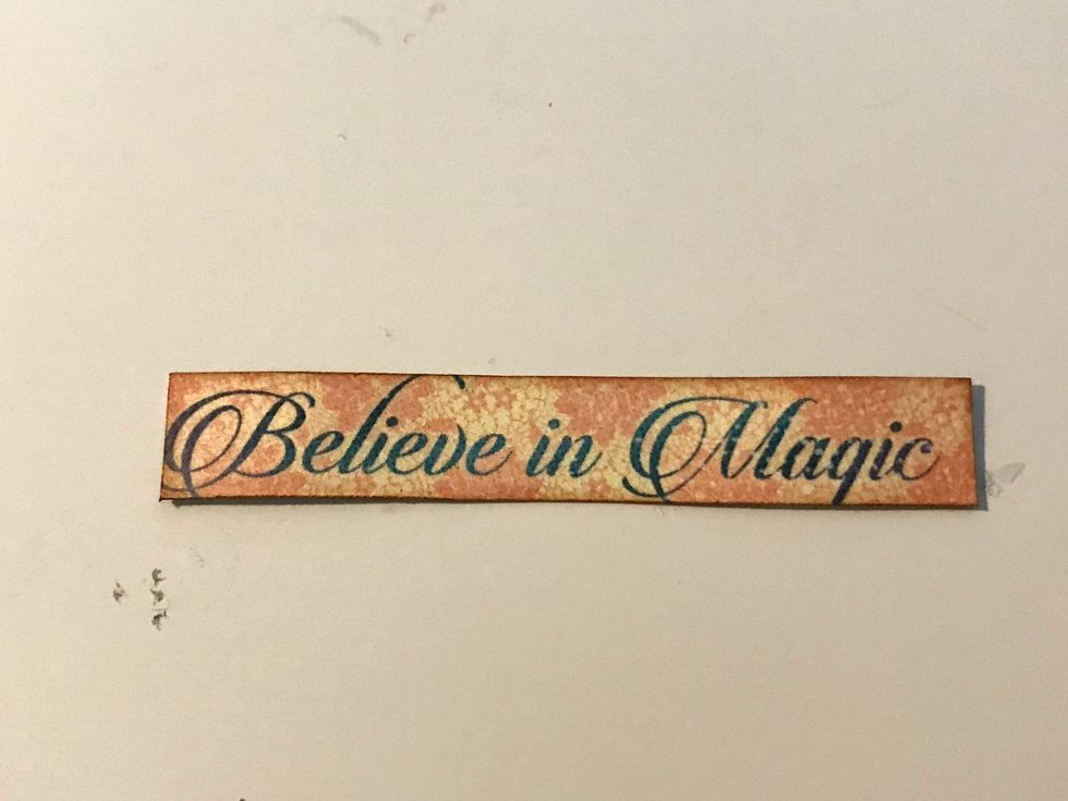 From the Magic Wishes paper, cut out the believe in magic sentiment. Ink the edges of the sentiment using Vintage Photo Distress Ink.
