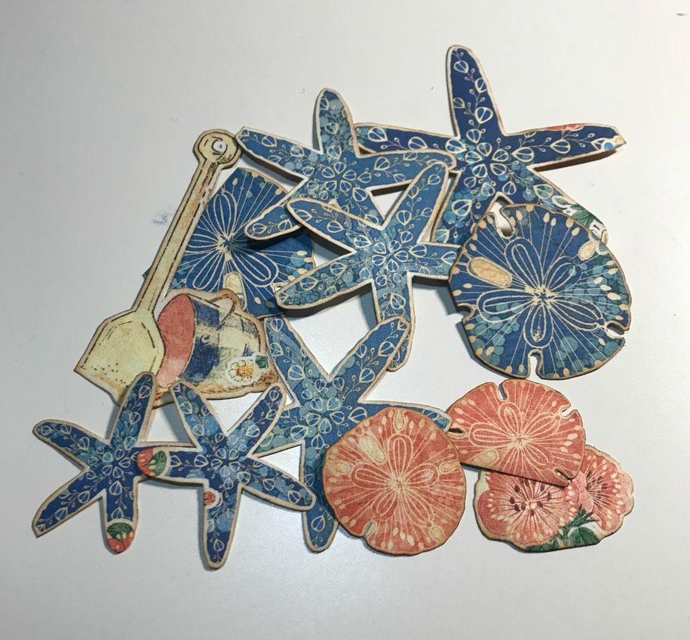 From the patterned papers, fussy cut 2 pick sand dollars, 2 sand dollar, 6 starfish and the bucket with shovel. Ink edges of the images using Vintage Photo Distress Ink & a blending tool with foam.