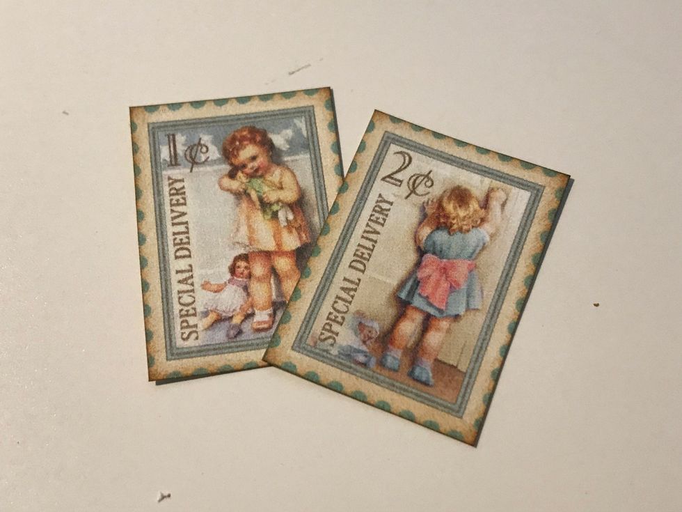 From the postage stamp paper, cut two stamps out. Ink the edges of the paper using Vintage Photo Distress Ink and a blending tool with foam.