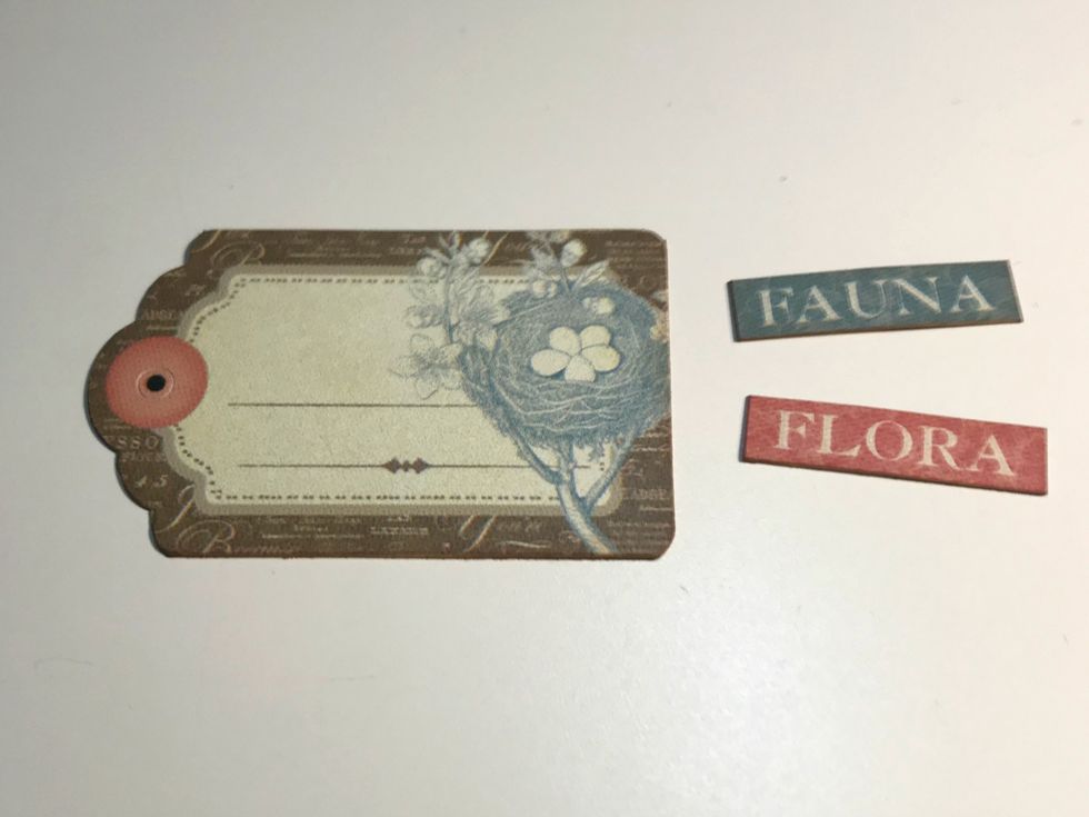 From the sticker sheet, adhere the tag, Flora and Fauna stickers to a piece of scrap paper. Cut the tag and words out. Ink the edges of the words & tag using Vintage Photo Distress Ink.