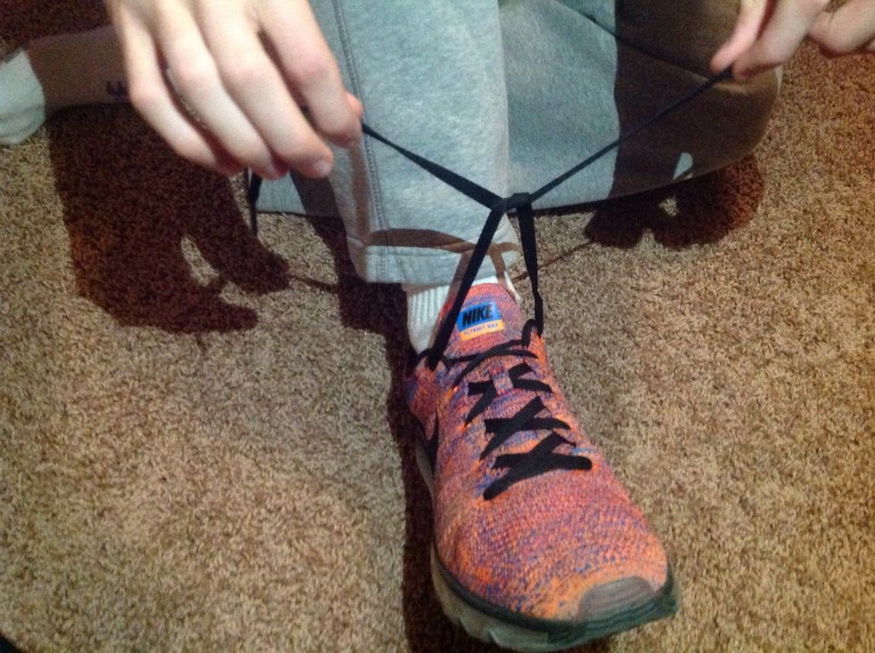 From the X shape, loop one lace under the other.