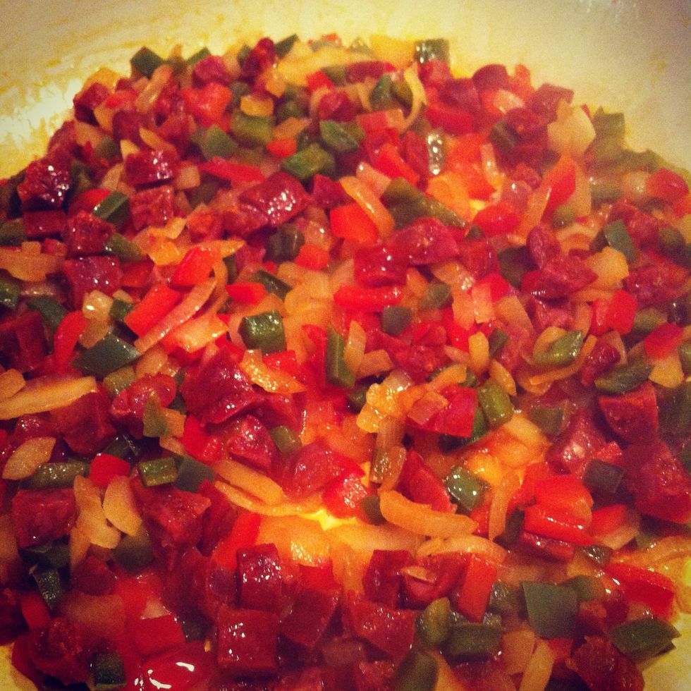 Fry the onion and peppers with a good glug of olive oil. Add the chopped chorizo and smoked bacon lardons and cook until the bacon is starting to brown  and the chorizo releases it's red oil.