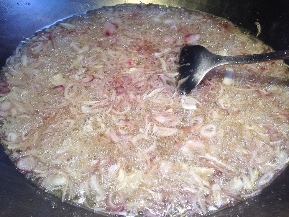 Fry the sliced shallots in hot oil until reddish brown and crispy.