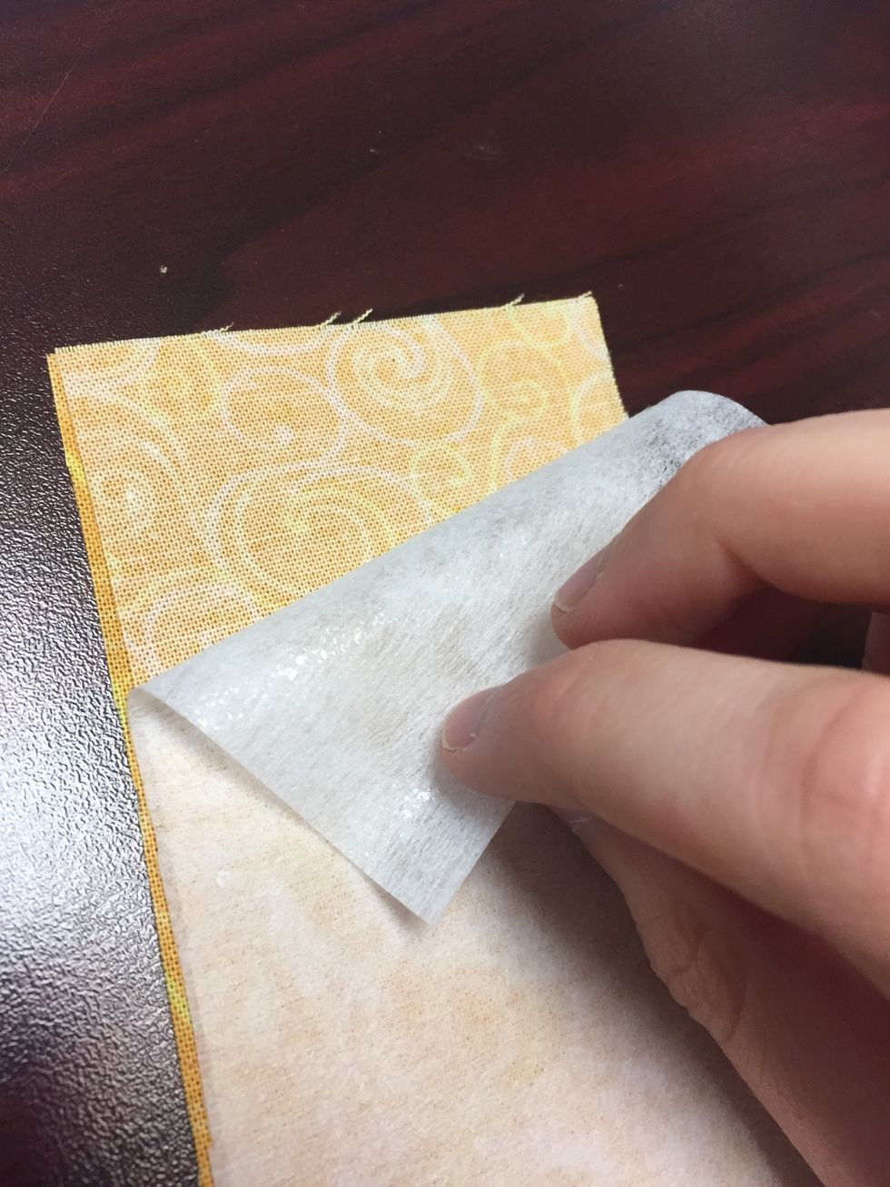 Fuse the interfacing to one of the fabric rectangles by lining up the glue side of the interfacing with the wrong side of the fabric and pressing it for a 15-20 seconds, then let the material cool.